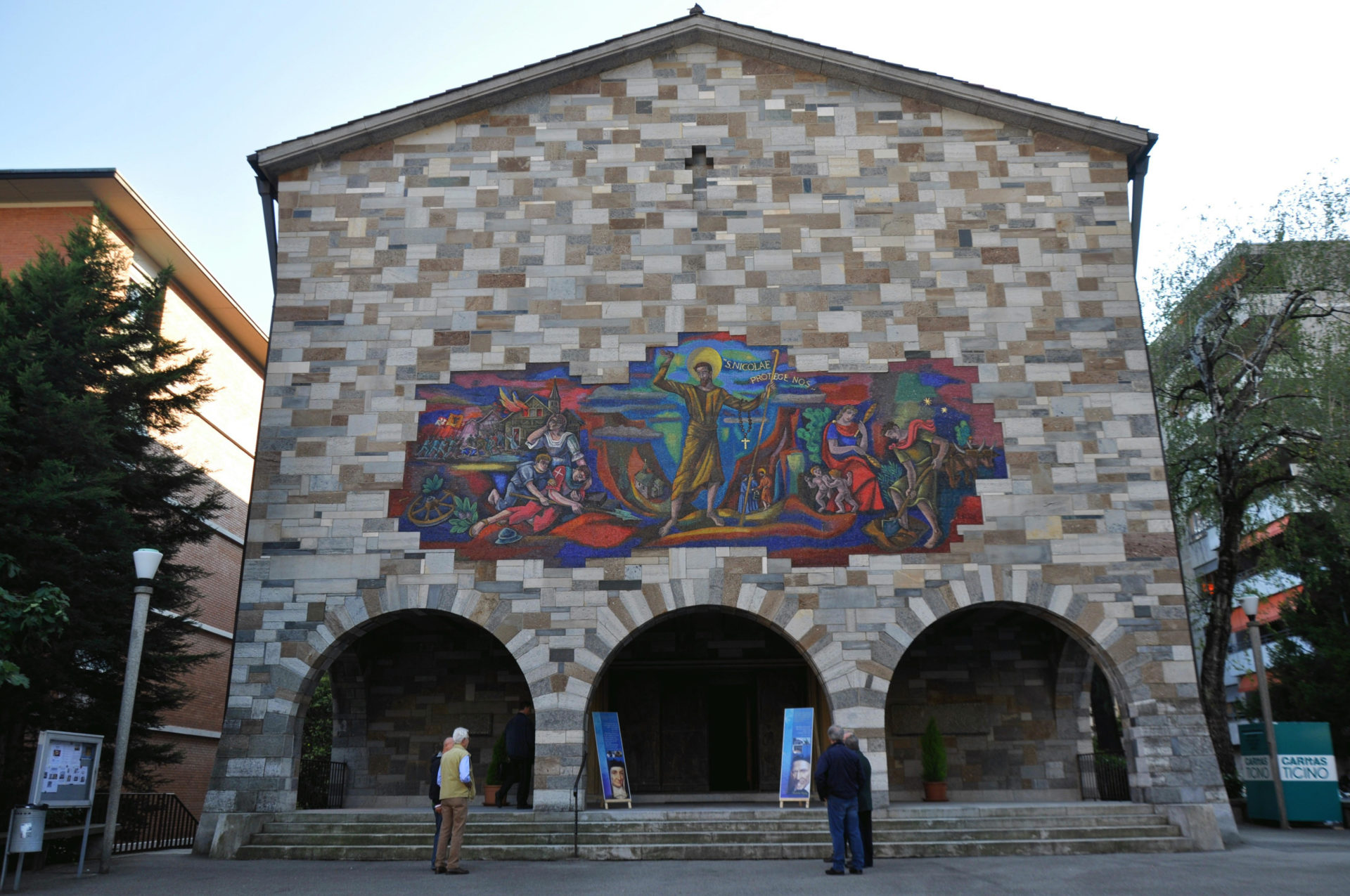 Aussenfassade der Kirche San Nicolao in Lugano-Besso mit dem Mosaik des Waadtländer Malers François Ribas (1903–1979). Es zeigt «den hl. Niklaus zwischen den Verwüstungen des Krieges und den Werken des Friedens. (© zvg)